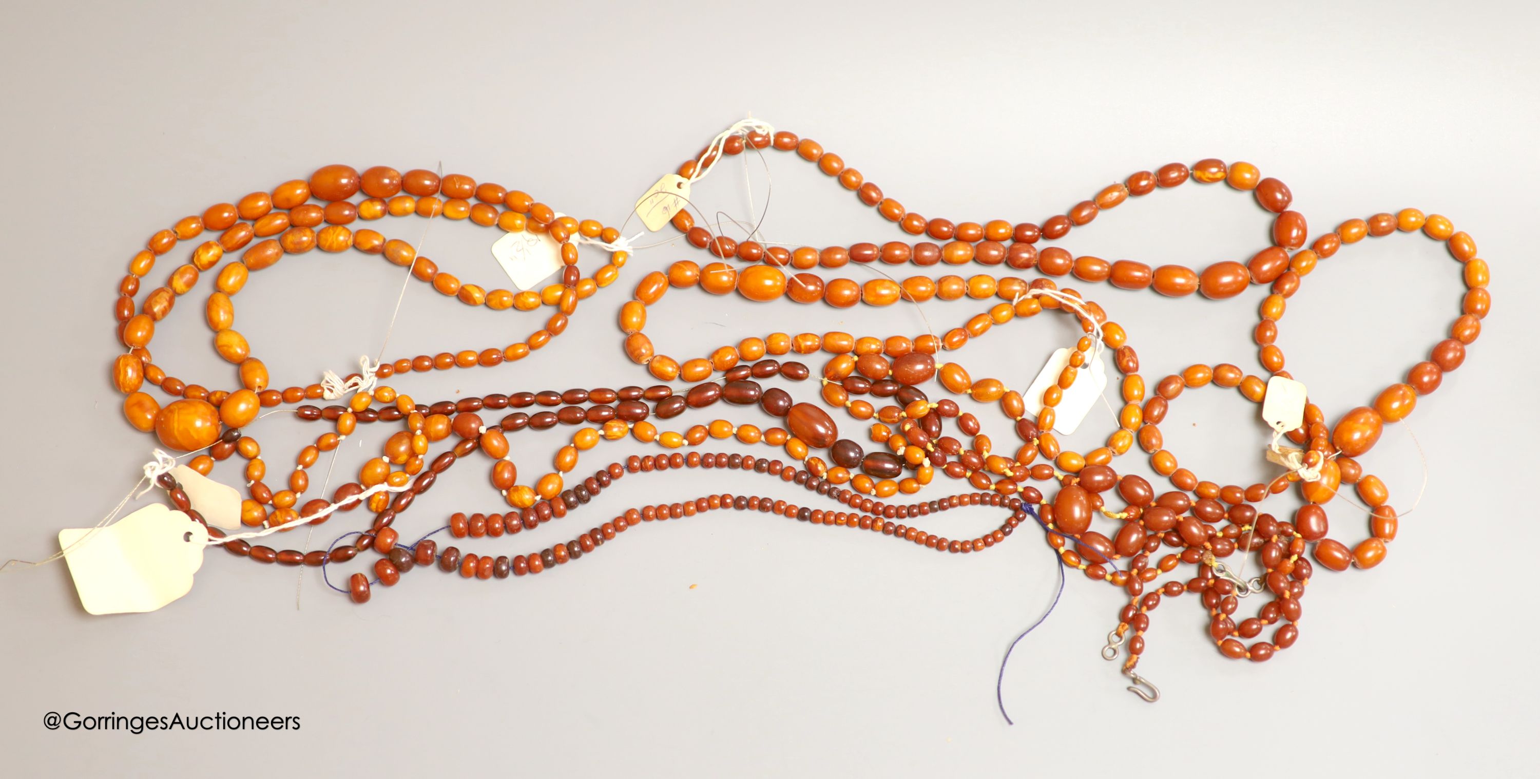 Nine assorted single strand amber bead necklaces, longest approximately 46cm, gross weight 173 grams and one simulated amber bead necklace.